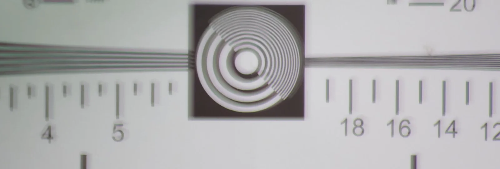 Resolution test chart photographed through a luxury brand sunglass lens, showing soft, low contrast detail