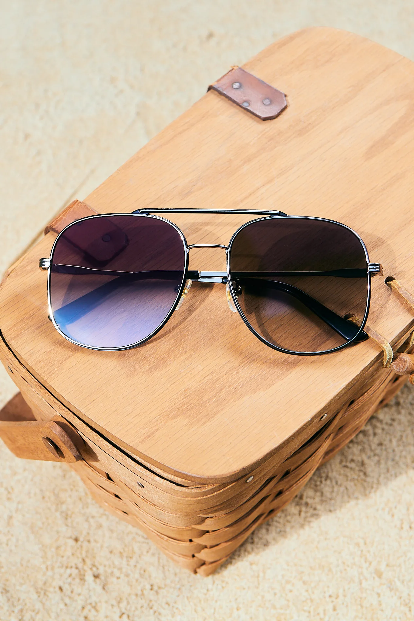 Kolari Shades aviators resting on a wooden case at the beach